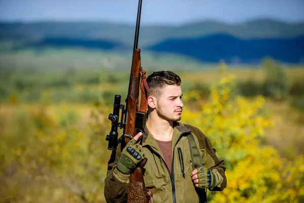 Der bärtige Jäger verbringt seine Freizeit auf der Jagd nach Vögeln. Jagd männliches Hobby Konzept. Mann brutalen Kerl Wildhüter Natur Hintergrund. Regulierung der Jagd. Jagdgewehr steht oben auf dem Berg — Stockfoto