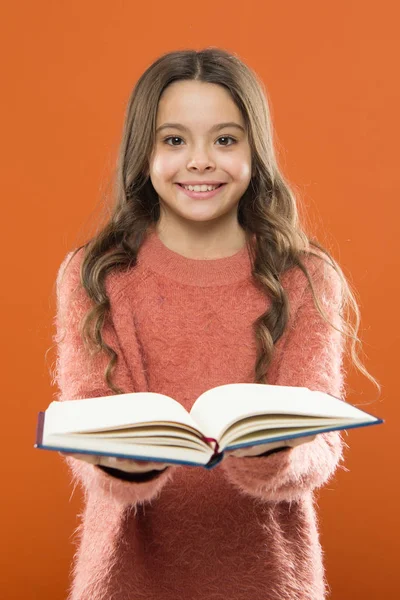 Ragazza tenere libro leggere storia su sfondo arancione. Bambino piace leggere il libro. Concetto di libreria. Meravigliosi libri gratuiti per bambini disponibili da leggere. Esercizio di lettura per bambini. Letteratura per bambini — Foto Stock