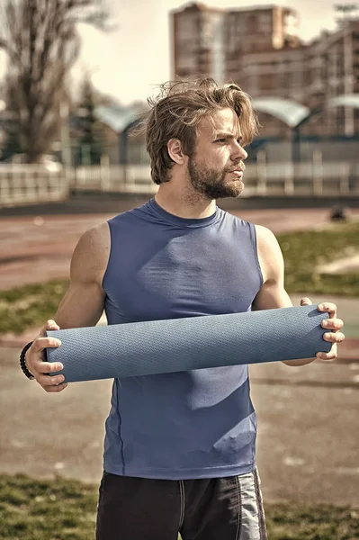 Hombre con cuerpo muscular, barba sosteniendo yoga o colchoneta de fitness —  Fotos de Stock