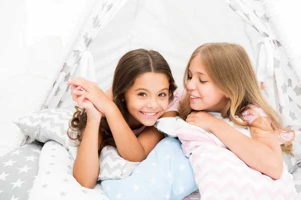 Las hermanas comparten chismes divirtiéndose en casa. Fiesta de pijamas para niños. Acogedora casa tipi lugar. Hermanas o mejores amigos pasar tiempo juntos yacen en casa tipi. Chicas divirtiéndose casa tipi. Ocio femenino — Foto de Stock