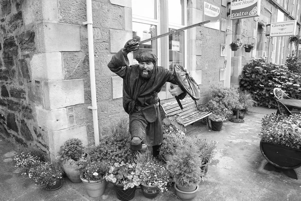 Oban, Reino Unido - 20 de febrero de 2010: estatua de guerrero en la esquina de la construcción con plantas de maceta. Casa de pueblo con banco y flores en patio. Arquitectura y diseño de estilo victoriano. Hotel alojamiento — Foto de Stock