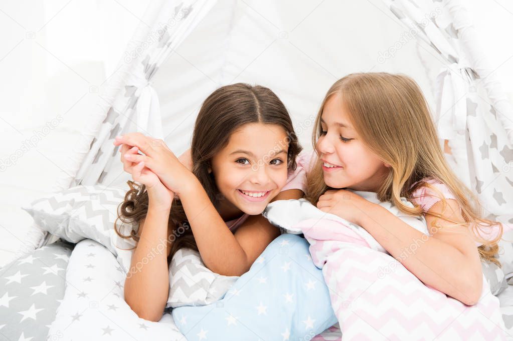 Sisters share gossips having fun at home. Pajamas party for kids. Cozy place tipi house. Sisters or best friends spend time together lay in tipi house. Girls having fun tipi house. Girlish leisure