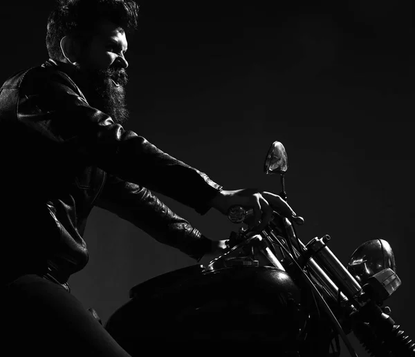 Macho, motociclista brutal em jaqueta de couro andar de moto à noite, espaço cópia. Conceito de masculinidade. Homem com barba, motociclista em jaqueta de couro sentado na moto do motor na escuridão, fundo preto — Fotografia de Stock