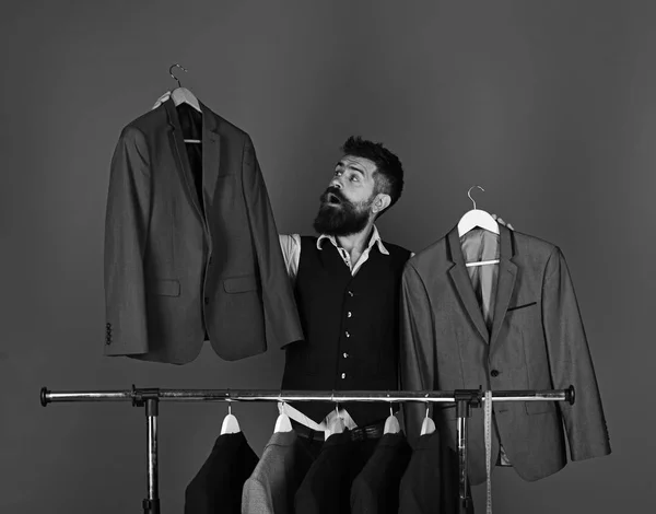 Designer makes choice near clothes hangers. Tailoring and design