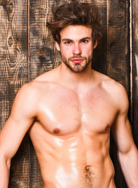 Спортсмен показывает сексуальный торс. Сексуальная грудь и живот холостяка. Мужчина спортсмен с подходящим туловищем. Парень соблазнительный взгляд мерцающей кожи. Сексуально привлекательный мачо взъерошенные волосы на деревянном фоне
