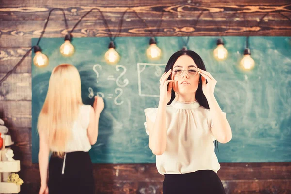 Kız çekici Bayan defocused kara tahta arka plan üzerinde yazma sırasında görünüyor. Öğrenci ve kursiyer kavramı. Çekici bir kadın ders için hazırlanıyor. Öğrenci, Öğretmen sınıfta gözlük standı — Stok fotoğraf