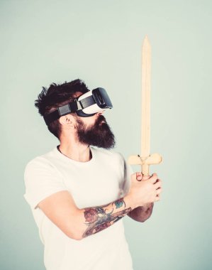 Hipster ciddi bir yüz üzerinde sanal gerçeklik oyun oyun keyfini çıkarın. Oyun kavramı. Adam kafa monte ekran ile kılıç tutan, dövüş Vr gözlük, açık mavi renkli sakallı Vr. adam oyunu oyna