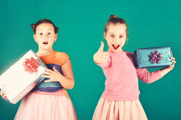 Niños con caras excitadas posan con regalos sobre fondo verde . — Foto de Stock