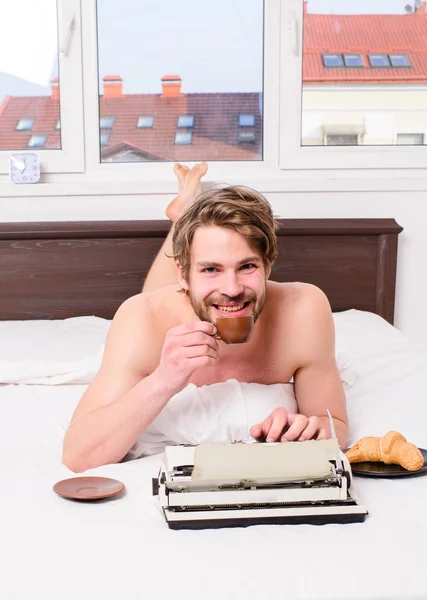 Hombre escritor acostado ropa de cama libro de trabajo. Autor desayunando en la cama beber café. Mañana inspiración. Café inspirándolo a escribir. Escritor autor romántico utiliza máquina de escribir a la antigua —  Fotos de Stock