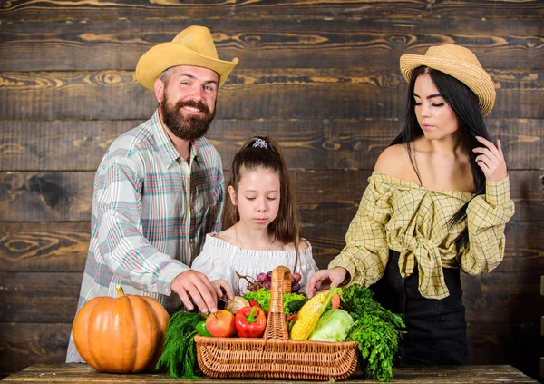 Harvest festival concept. Family farmers with harvest wooden background. Family rustic style farmers market with fall harvest. Parents and daughter celebrate harvest holiday pumpkin vegetables basket