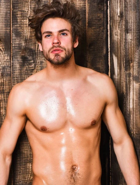 Sportsman show six pack sexy torso. Bachelor sexy body chest and belly. Guy seductive glance shimmering skin. Sexy attractive macho tousled hair on wooden background. Man athlete with fit torso