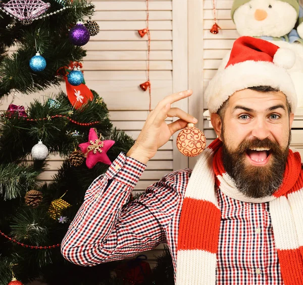 Mann mit Bart hält goldene Weihnachtskugeln als Ohrringe — Stockfoto