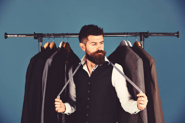 Бизнесмен с серьезным лицом рядом куртки на синем фоне