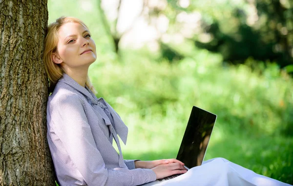 Природный офис. Преимущества работы на открытом воздухе. Женщина с ноутбуком работает на открытом воздухе постное дерево. Минута отдыха. Девушка, работающая с ноутбуком в парке, сидит на траве. Образовательные технологии и интернет-концепция — стоковое фото