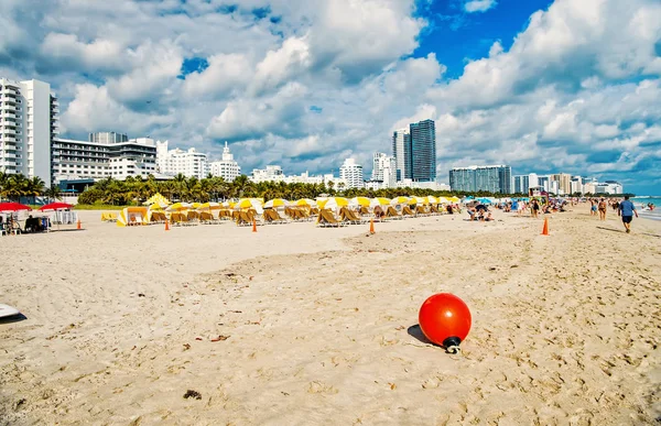 Spiaggia di sabbia con sdraio sotto ombrellone giallo — Foto Stock