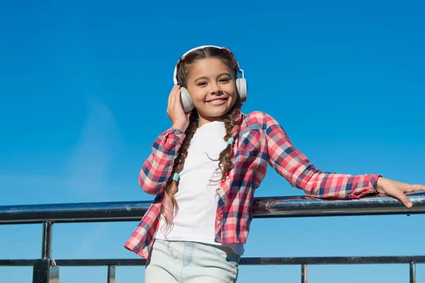 Haga feliz a su hijo con los auriculares para niños mejor calificados disponibles en este momento. Niña escuchar música al aire libre con auriculares modernos. Disfruta de la música en todas partes. Las mejores aplicaciones de música que merecen una escucha — Foto de Stock