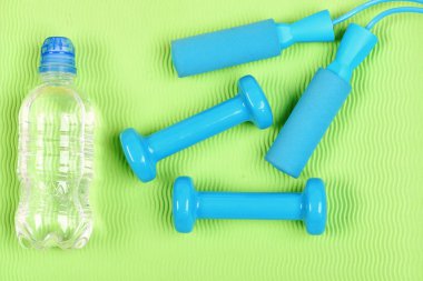 Halterler ve halat atlama su şişesinin yanında.