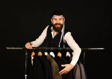 Siyah arka plandaki ceketlerin yanında neşeli yüzlü bir iş adamı..