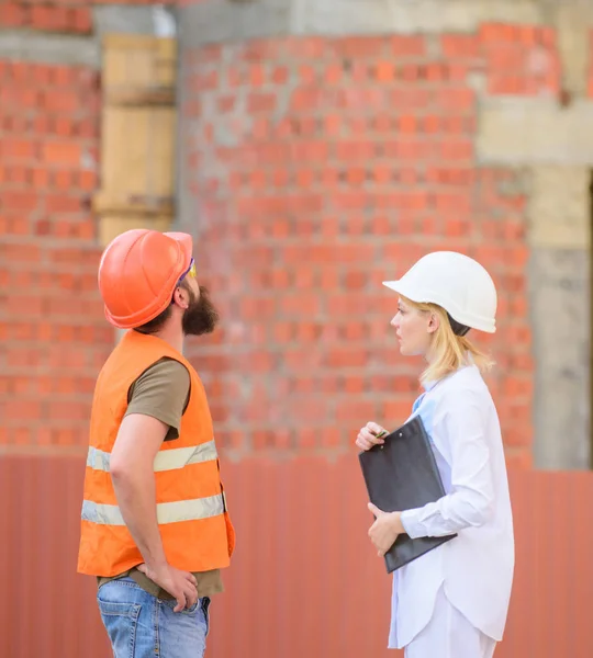 Discuter du plan de progrès. Concept d'industrie de la construction. Relations client de construction et industrie de la construction participante. Femme ingénieur et barbu constructeur brutal discuter des progrès de la construction — Photo