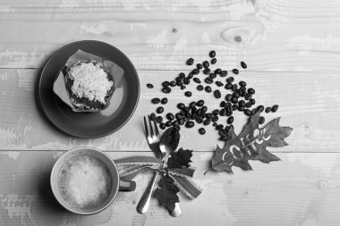 Yazılı kelime kahve ile yaprak. Seramik sofra kahve, en iyi manzaralı. Cappuccino kahve sonbahar ahşap zemin üzerine bırakır, kahve çekirdekleri, cupcake, kaşık ve çatal. Kahve saati kavramı