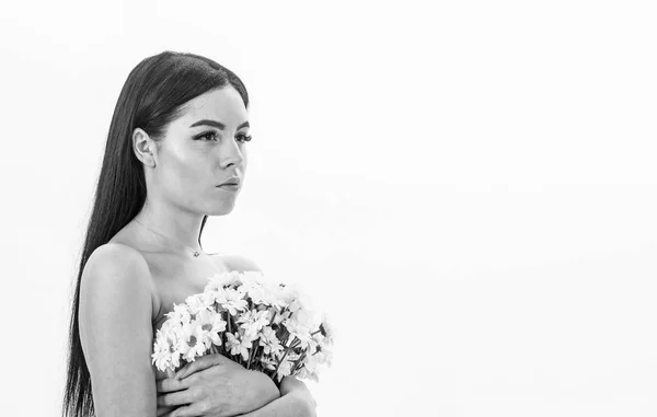 La signora copre i seni con dei fiori, isolati sul bianco. Donna che nasconde i seni, copre con bouquet. Ragazza sul viso calmo nudo tiene fiori di camomilla davanti al petto. Cancro del concetto di seno — Foto Stock