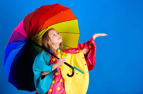 Accessori impermeabili per bambini. Godetevi il tempo piovoso con indumenti adeguati. Gli accessori impermeabili rendono la giornata piovosa allegra e piacevole. Ragazza felice tenere colorato ombrello indossare mantello impermeabile — Foto Stock