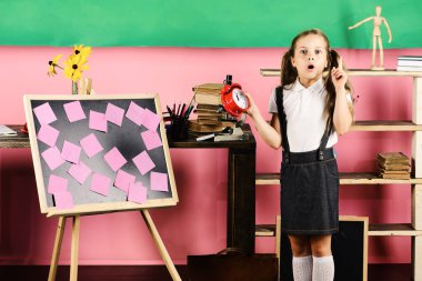 Sürpriz yüz fikir sahip olmak ile kız öğrenci kırmızı saat tutar