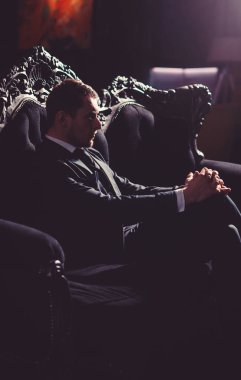 Avukat ciddi tıraşsız yüzü. İşadamı zarif vintage koltukta oturur ve düşünüyor. Mesleki başarı, iş, moda, zenginlik kavram. Yönetmen şık elbiseli saygıdeğer görünüyor