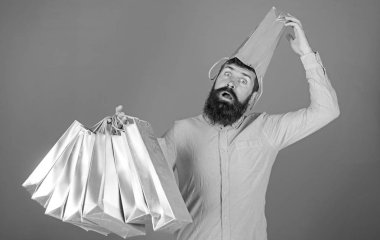 Adam sakal ve bıyık taşır alışveriş torbaları, mavi arka plan ile. Satış sezon indirimlerle alışveriş adam. Alışveriş kavramı. Kafasında torba ile sürpriz yüzündeki hipster bağımlısı Alışverişkoliğin olduğunu