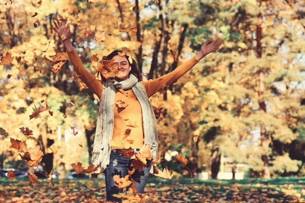 Autumn leaves falling on happy young woman
