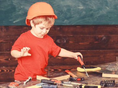Çocuk Çocuk Tornavida Aracı tutar. Handcrafting ve atölye kavramı. Kask Oluşturucu veya repairer, veya handcrafting şirin çocuk. Yürümeye başlayan çocuk meşgul yüzündeki tornavida ile Atölyesi'nde oynamaktadır.
