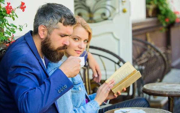 Love and flirt. Common interests. Romantic date. Couple in love sit cafe terrace. Man with beard and blonde woman cuddle on romantic date. Romance concept. Couple flirting romantic date read book — Stock Photo, Image