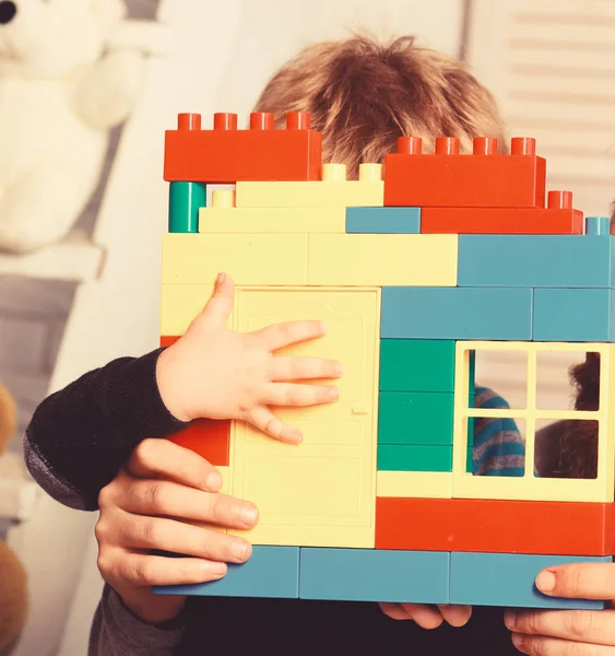 Las manos masculinas y el niño sostienen coloridos ladrillos de juguete construcción . — Foto de Stock