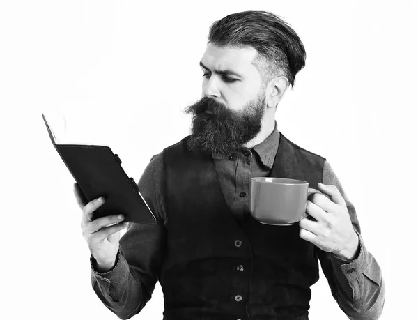 Barbudo hombre leyendo bloc de notas, taza de té con cara seria — Foto de Stock