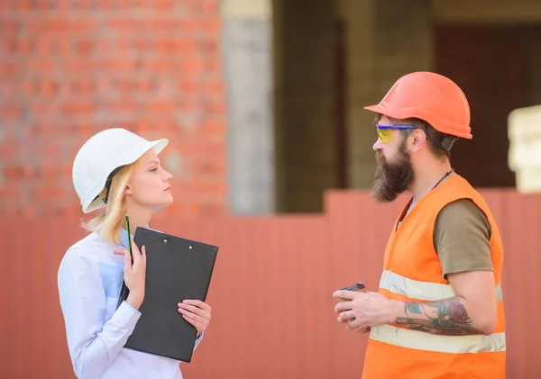 Relationships construction client and participant building industry. Discuss progress plan. Woman engineer and bearded brutal builder discuss construction progress. Construction industry concept