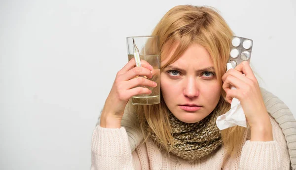 Las mujeres usan bufanda caliente porque la enfermedad o la gripe. Niña mantenga tabletas de agua de vidrio y termómetro fondo de luz de cerca. Deshazte de la gripe. Conseguir alivio rápido. Maneras de sentirse mejor rápido. Remedios caseros —  Fotos de Stock