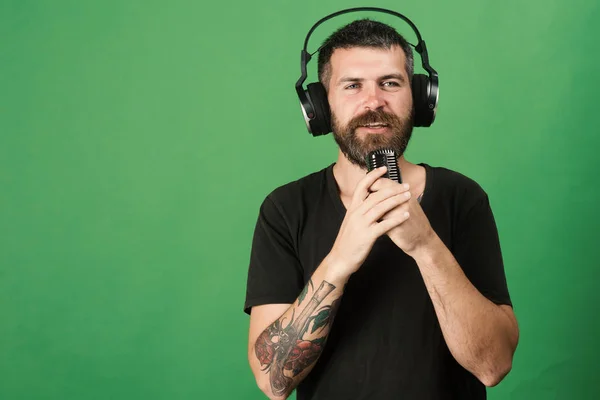 Dj com barba usa fones de ouvido, espaço de cópia. Homem detém microfone — Fotografia de Stock