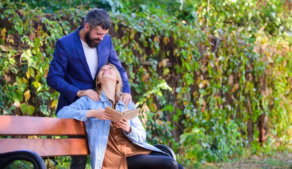 Romantic relations concept. Couple in love romantic date nature park background. Girl sit bench read book while wait boyfriend. Wait him for date. Dating in park. Park best place for romantic date