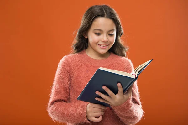 Activités de lecture pour les enfants. Fille tenir livre lire l'histoire sur fond orange. L'enfant aime lire le livre. Concept de librairie. Magnifiques livres gratuits pour enfants disponibles à la lecture. Littérature pour enfants — Photo