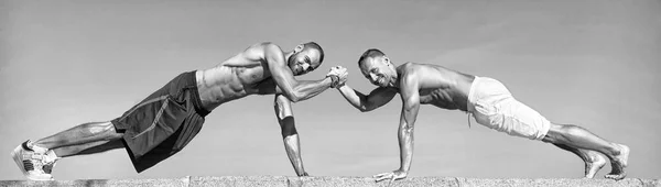 Push ups uitdaging. Mannen gemotiveerde training samen. Sporters verbetert zijn kracht door oefening push-up. Uithoudingsvermogen verbeteren door push-ups. Mannen doen push-up buiten blauwe hemelachtergrond. Teamwork concept — Stockfoto