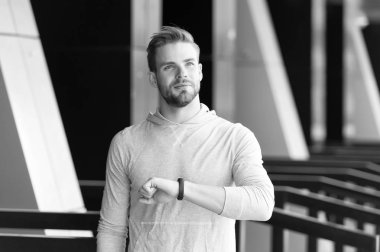 Adam atlet memnun yüz zaman, kentsel arka plan kontrol. Kıl fitness izci veya pedometer ile sporcu zamanında tamamlandı. Sporcu pedometre gadget ile eğitim. Sadece zaman kavramı üzerinde