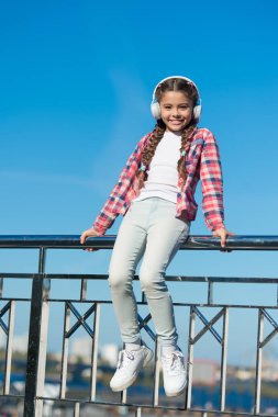 Her yerde müziğin tadını çıkar. Dinlemeyi hak eden en iyi müzik uygulamaları. Çocuğunuzu en iyi çocuk kulaklıklarıyla mutlu edin. Kız çocuk açık havada modern kulaklıklarla müzik dinliyor.
