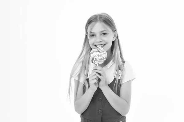Flicka på leende ansikte håller jätte färgglada lollipop i hand, isolerad på vit bakgrund. Barn med långt hår gillar sötsaker och fester. Sweet tooth koncept. Flicka äter stora godis på pinne eller lollipop — Stockfoto