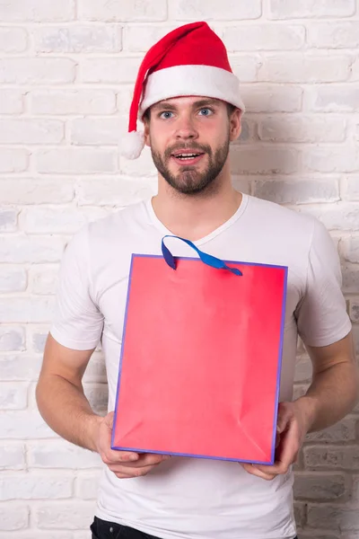 Mannen i santa hatt hålla julklapp. Online julhandeln. Gott nytt år, kopia utrymme. leverans julklappar. På morgonen innan Xmas. santa lycklig. Kontor julfest — Stockfoto