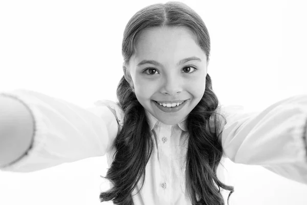 셀카 타임. 학교 유니폼을 입은 똑똑 한 아이가 행복 한 표정을 짓습니다. 귀엽고 곱슬곱슬 한 여자 아이는 스마트폰을 들고 셀카의 흰색 배경을 받아들입니다. 여대생의 교복은 스마트폰을 들고 있다 — 스톡 사진