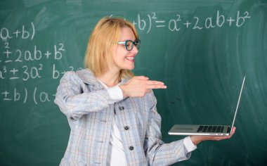 Kadın laptop ekranında silah hareketi ile işaret tutar. Eğitimci akıllı zeki Bayan modern dizüstü bilgisayar ile silah jest kara tahta arka plan kalın. Eğitim reformları kavramı. Hedefi hakkında bilgi