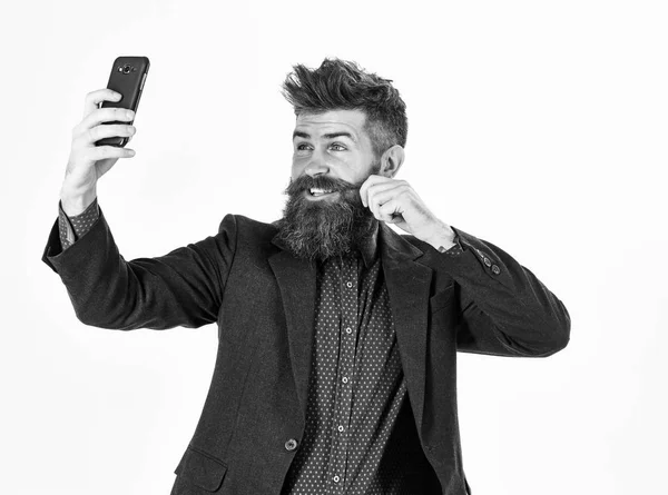 Un homme brutal au visage joyeux. L'homme barbu sourit et fait un autoportrait. Hipster avec longue barbe et visage heureux. Selfie, coiffure, concept de réseau social. Mode et style, nouvelles technologies — Photo