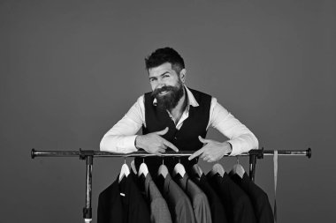 Tezgahtar ya da satıcı elbise askılarına yaslanır.