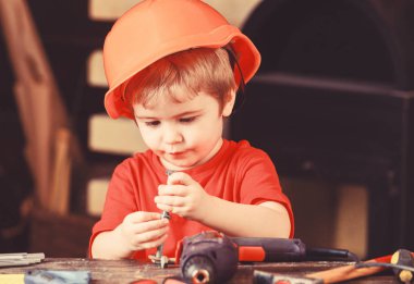 Baret, Oluşturucusu'nu veya repairer, handcrafting onaltılık cıvata ile oynarken kask çocuk. Yürümeye başlayan çocuk meşgul yüzündeki evde atölyede civata ile oynuyor. Kavram handcrafting. Çocuk Çocuk tamirci oynamak