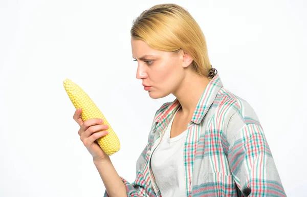 Informação sobre o valor nutricional. Rapariga praticar comer alimentos não cozidos e não processados. Produto vegetariano. Mulher agricultor escolher espiga de milho amarelo no fundo branco. Menina estilo rústico segurar milho maduro — Fotografia de Stock